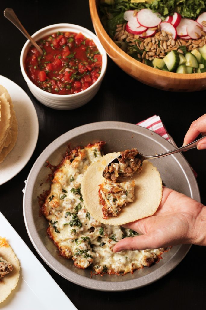 scooping queso fundido into a corn tortillas.