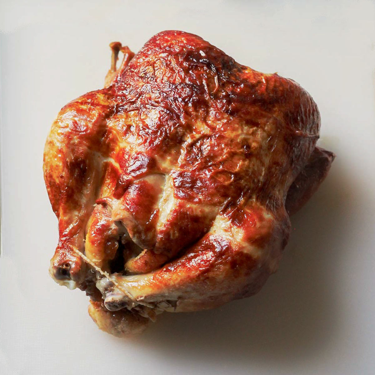 whole roast chicken on a white cutting board.