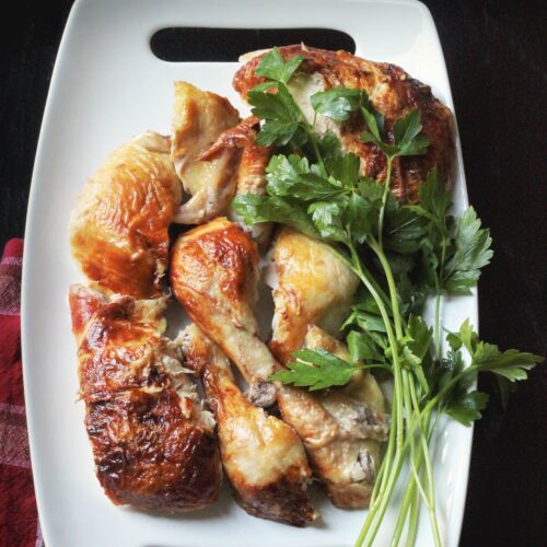 carved chicken pieces on a platter with fresh herbs.