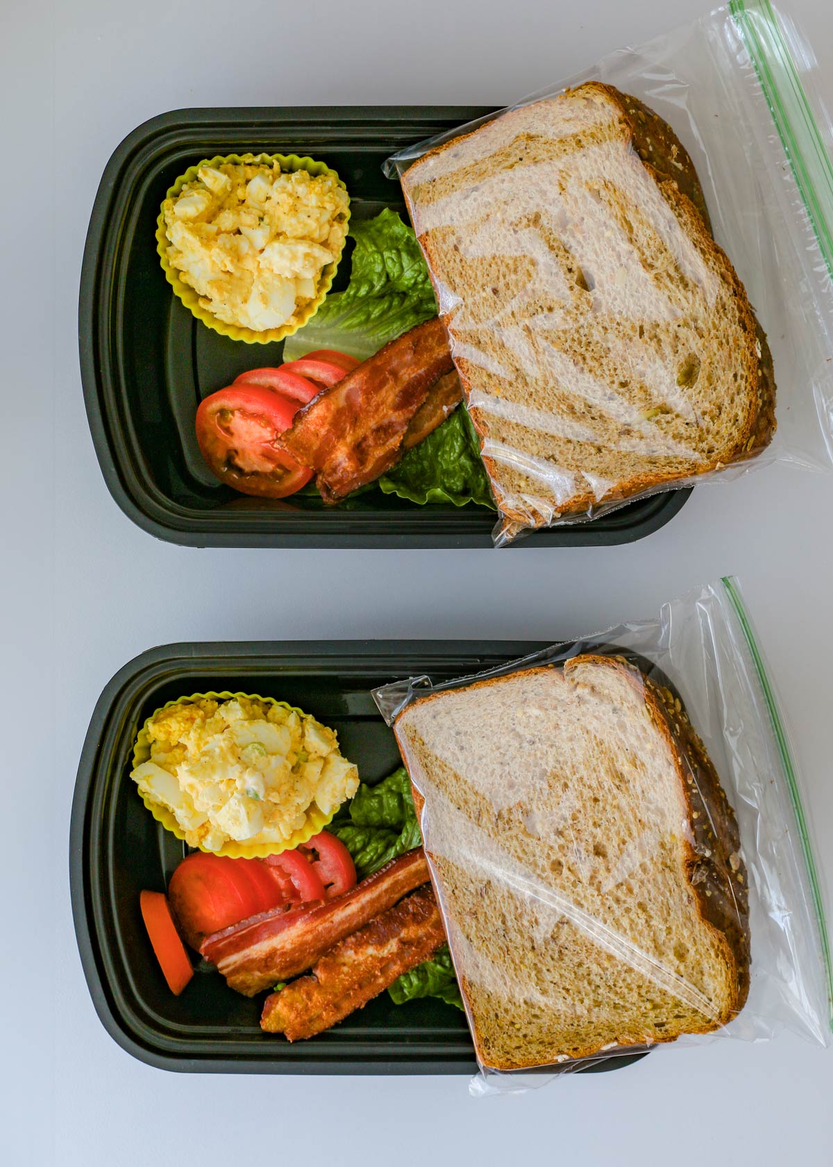 blt egg sandwiches prepped in meal prep boxes, with the bread in plastic bags.