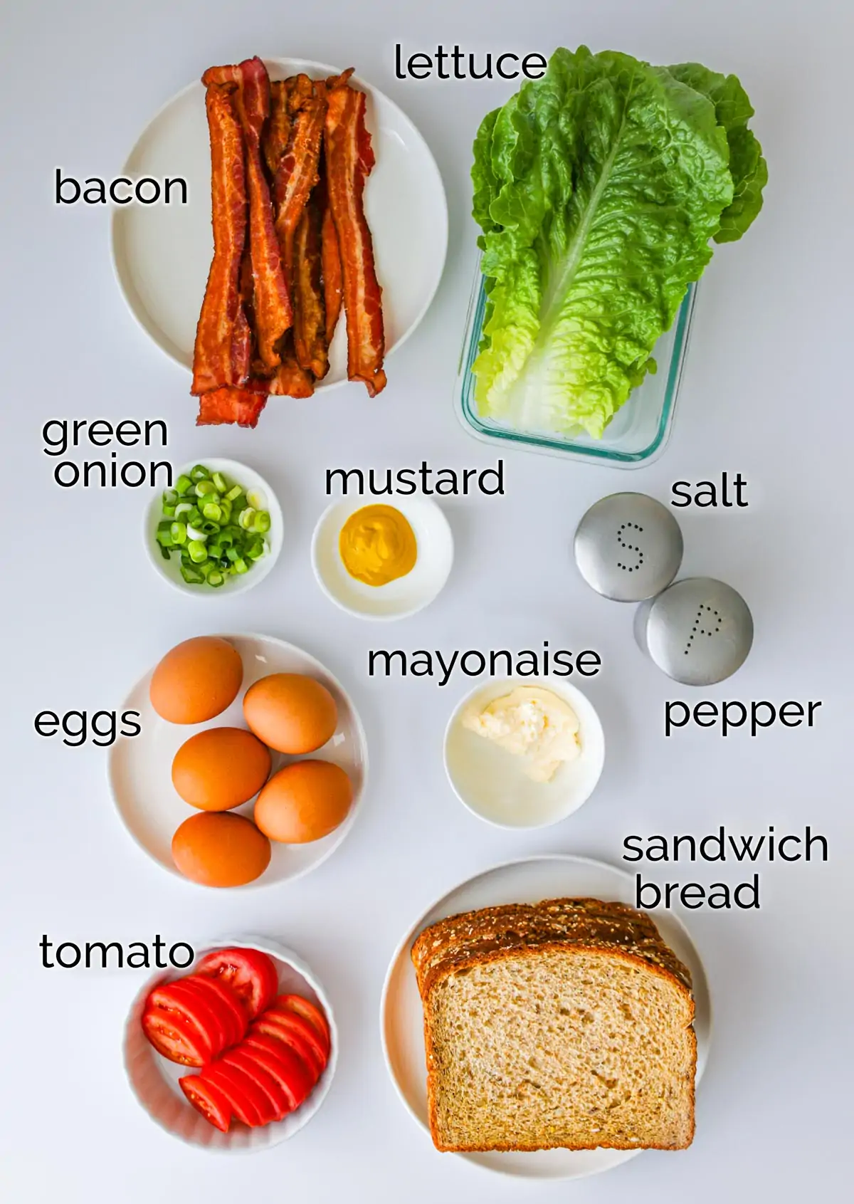ingredients for egg salad BLT sandwiches laid out on white counter.