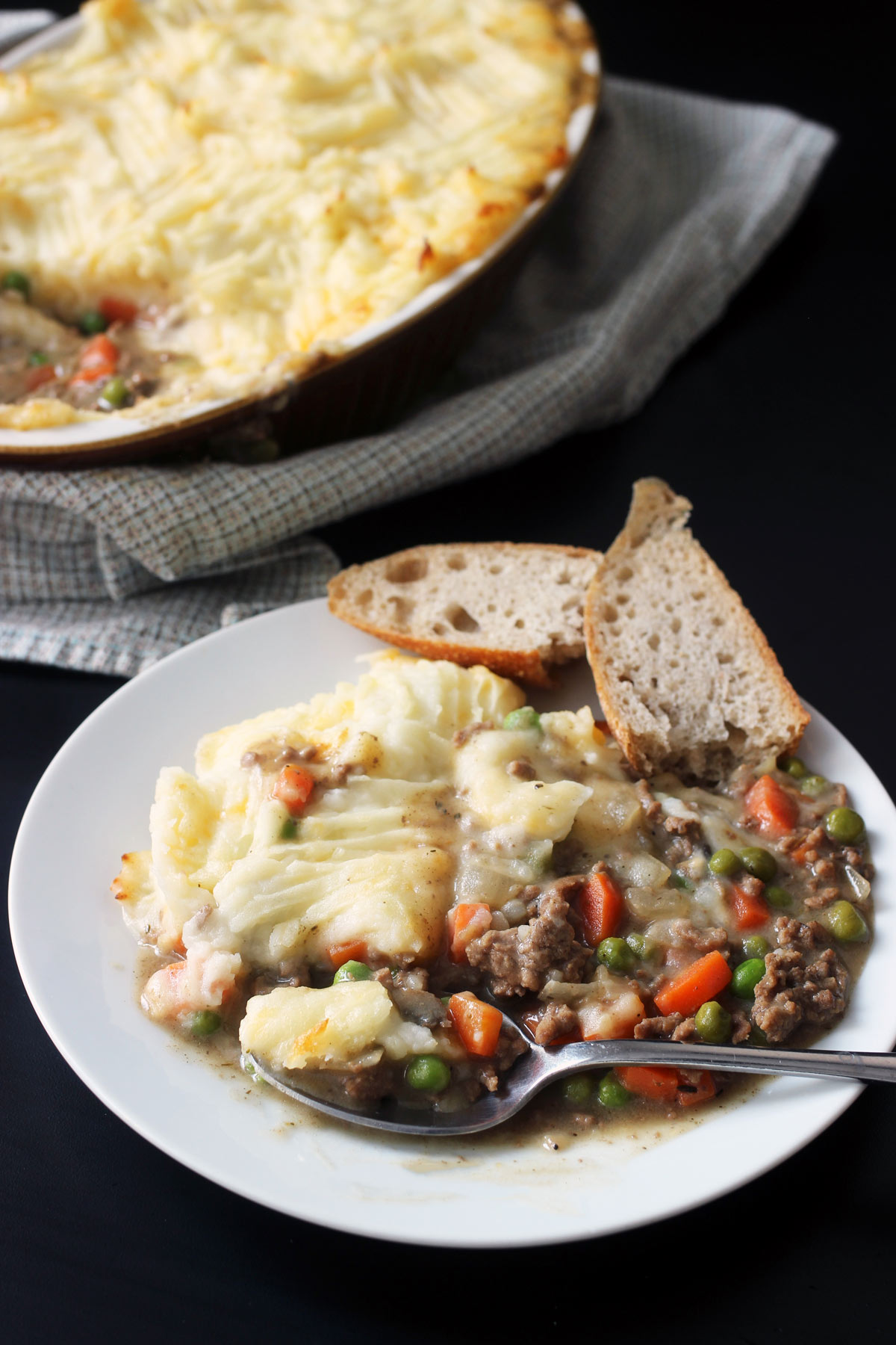 shepherd's pie on plate with spoon and bread