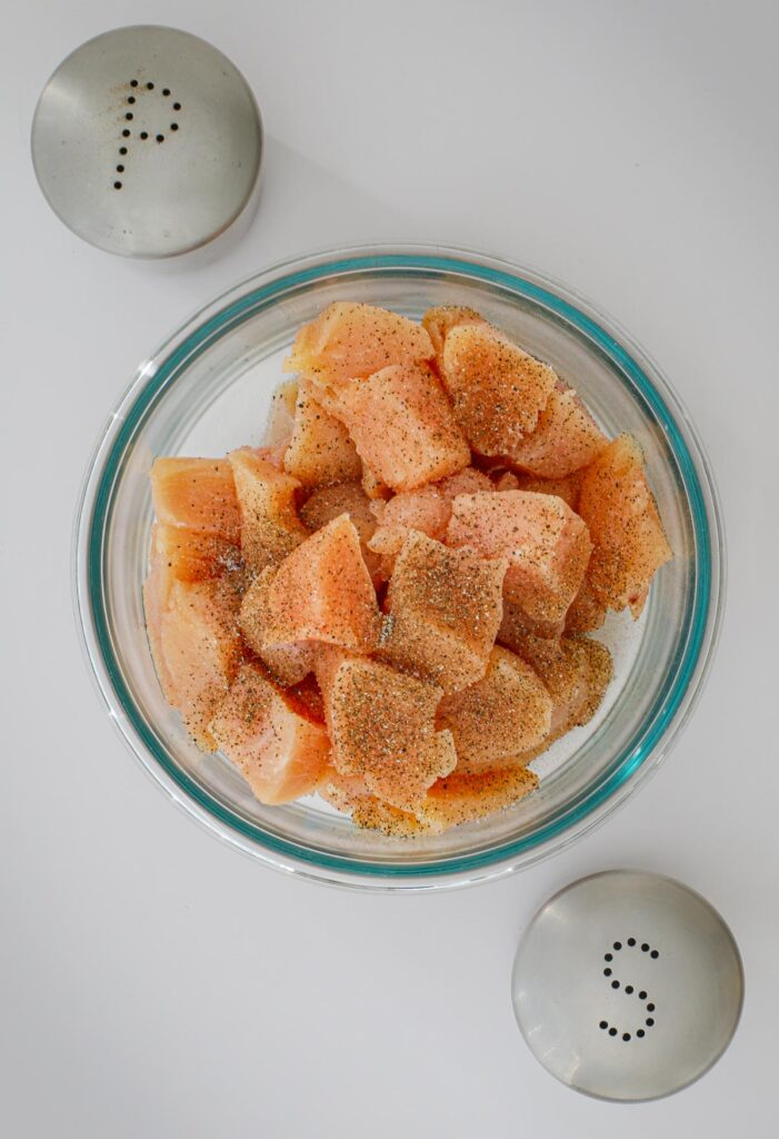 chicken cubes seasoned with salt and pepper in bowl.