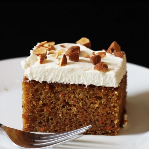 close up of a square of carrot cake on a white plate.