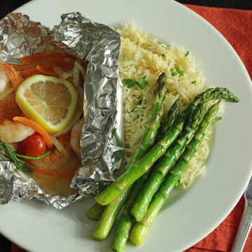 fish packet, rice, and asparagus on plate