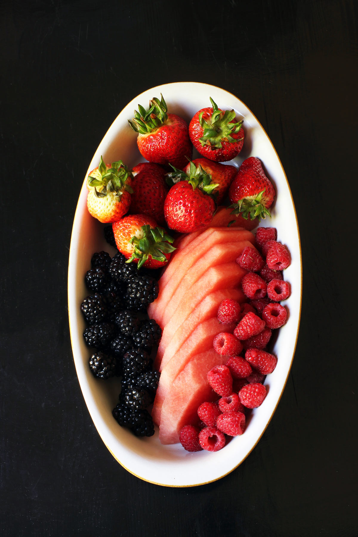 oval fruit tray with berries and watermelon slices.