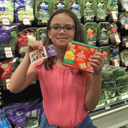 girl in grocery store with coupon and box