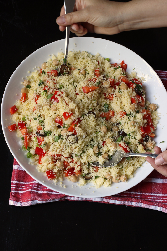 bowl of couscous salad with serving hands