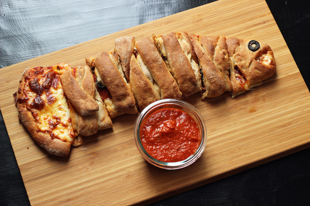 A pizza sitting on top of a wooden cutting board, with Calzone