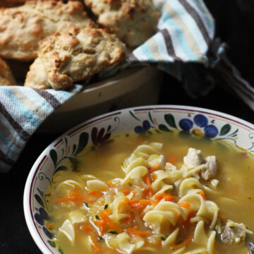 bowl of chicken noodle soup and basket of biscuits