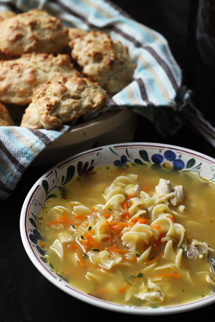bowl of chicken noodle soup and basket of biscuits