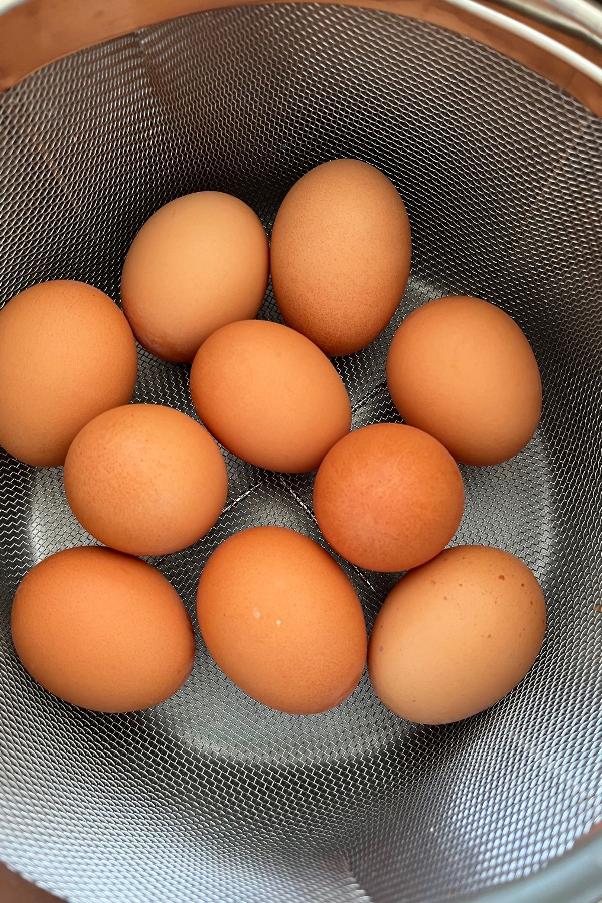 brown eggs in a metal basket in the insert of an instant pot.