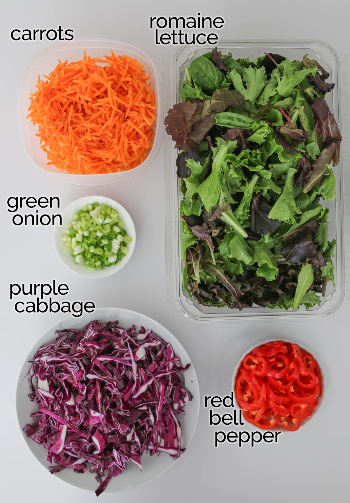 ingredients for meal prep salads laid out on white counter.