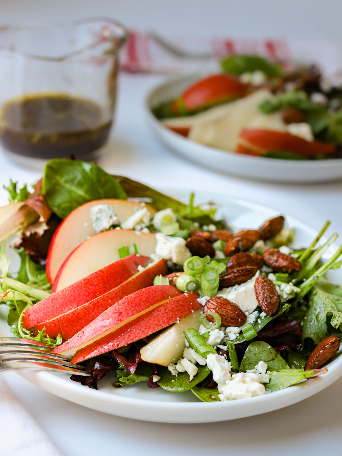 pear salads on white counter with small pitcher of balsamic vinaigrette.