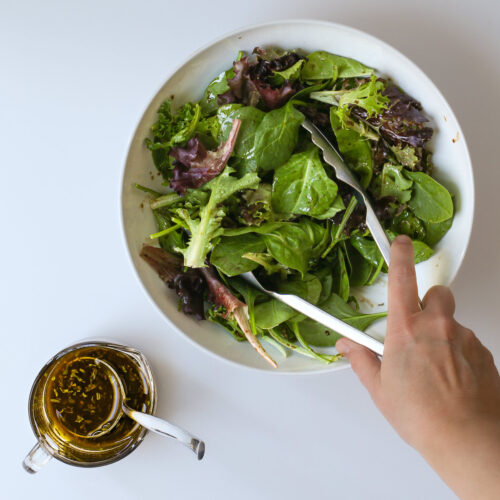tossing balsamic dressing with mixed greens.