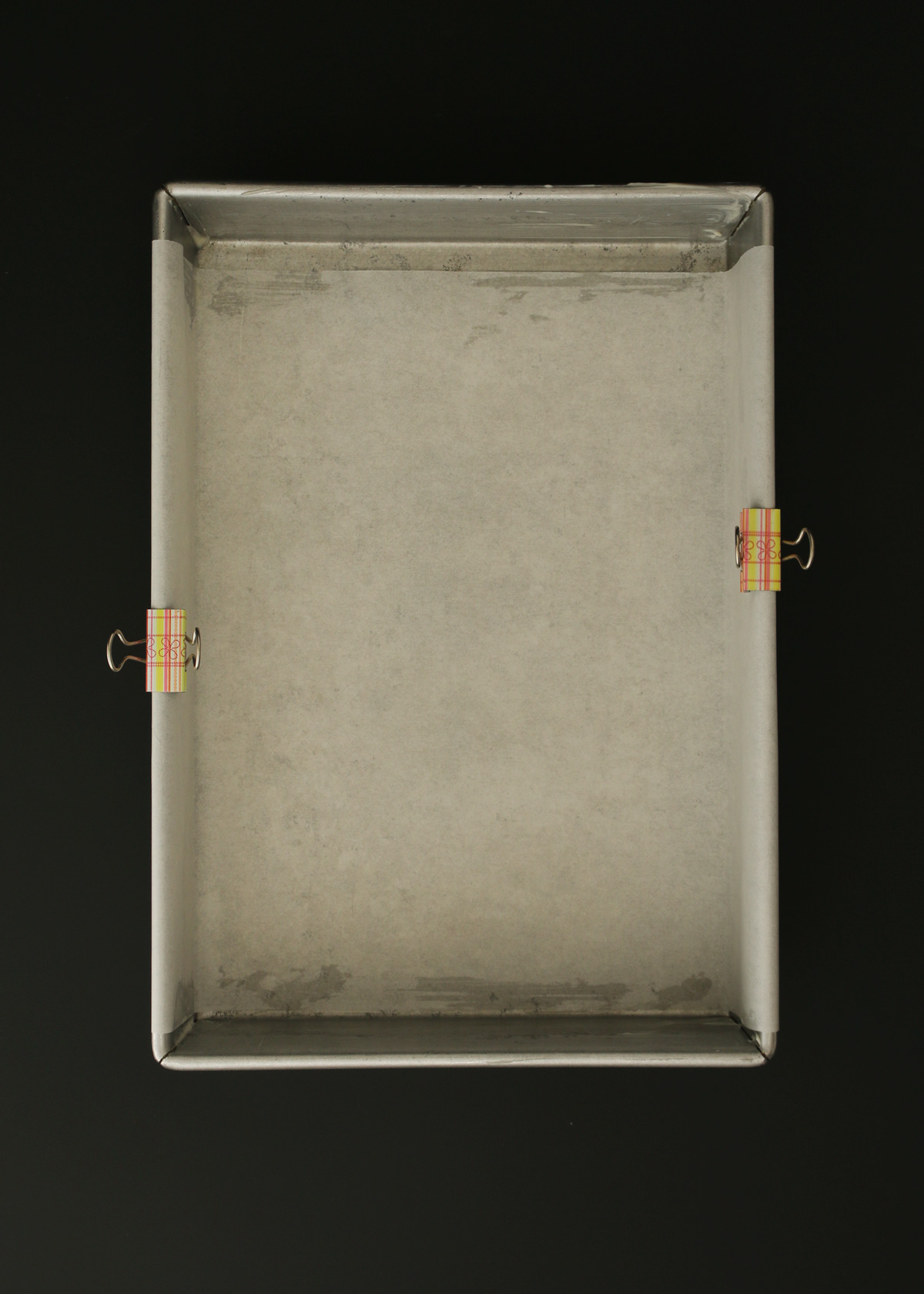 9X13-inch pan lined with parchment paper held on with binder clips.