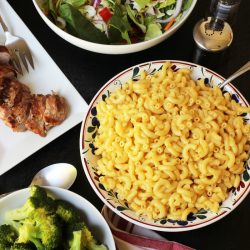 table set with mac and cheese salad pork and broccoli