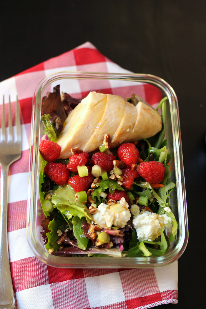 glass dish with salad, chicken, and raspberries