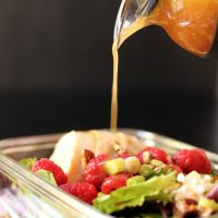 pouring raspberry vinaigrette onto salad
