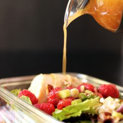 pouring raspberry vinaigrette onto salad