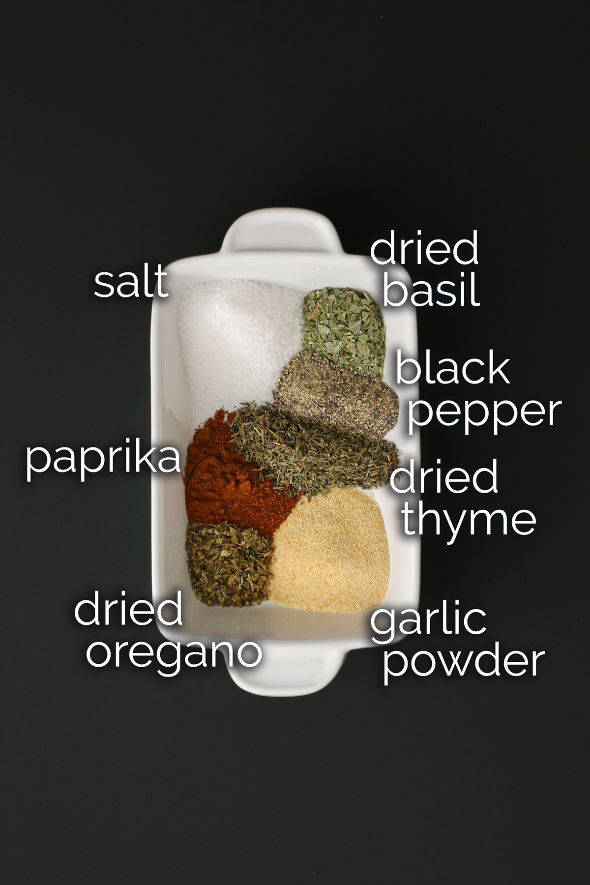 ingredients for seasoned salt measured out in a large white dish.