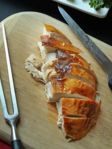 turkey breast on cutting board with knife and carving fork.