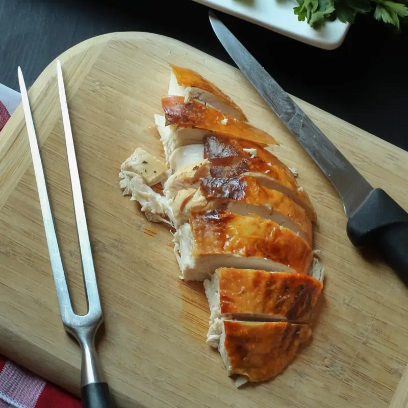 turkey breast on cutting board with knife and carving fork.