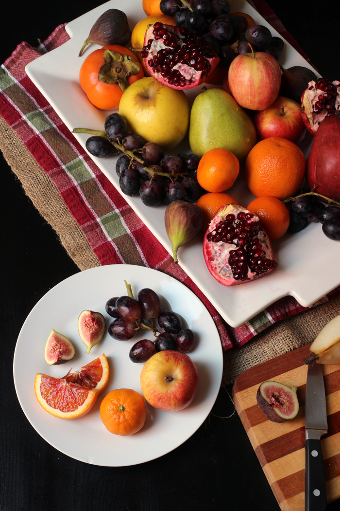 plate of cut fruit next to platter with knife and cutting board