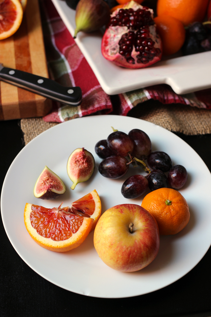 plate of fig orange apple and grapes