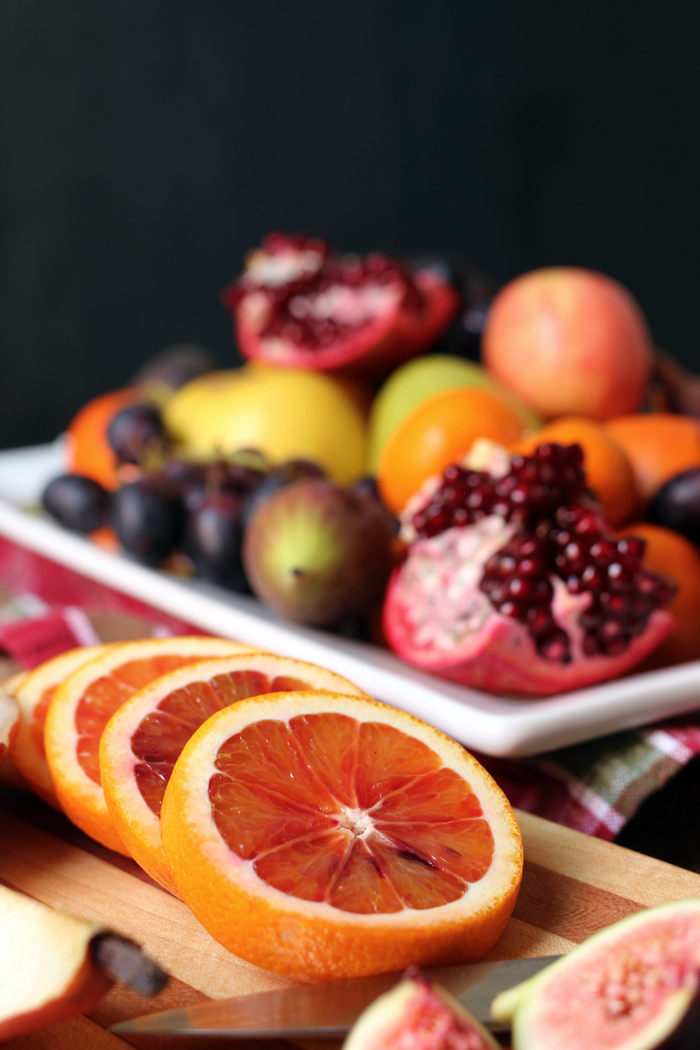 sliced blood orange on board next to fruit platter