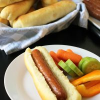 hot dog on homemade bun on plate with vegetables