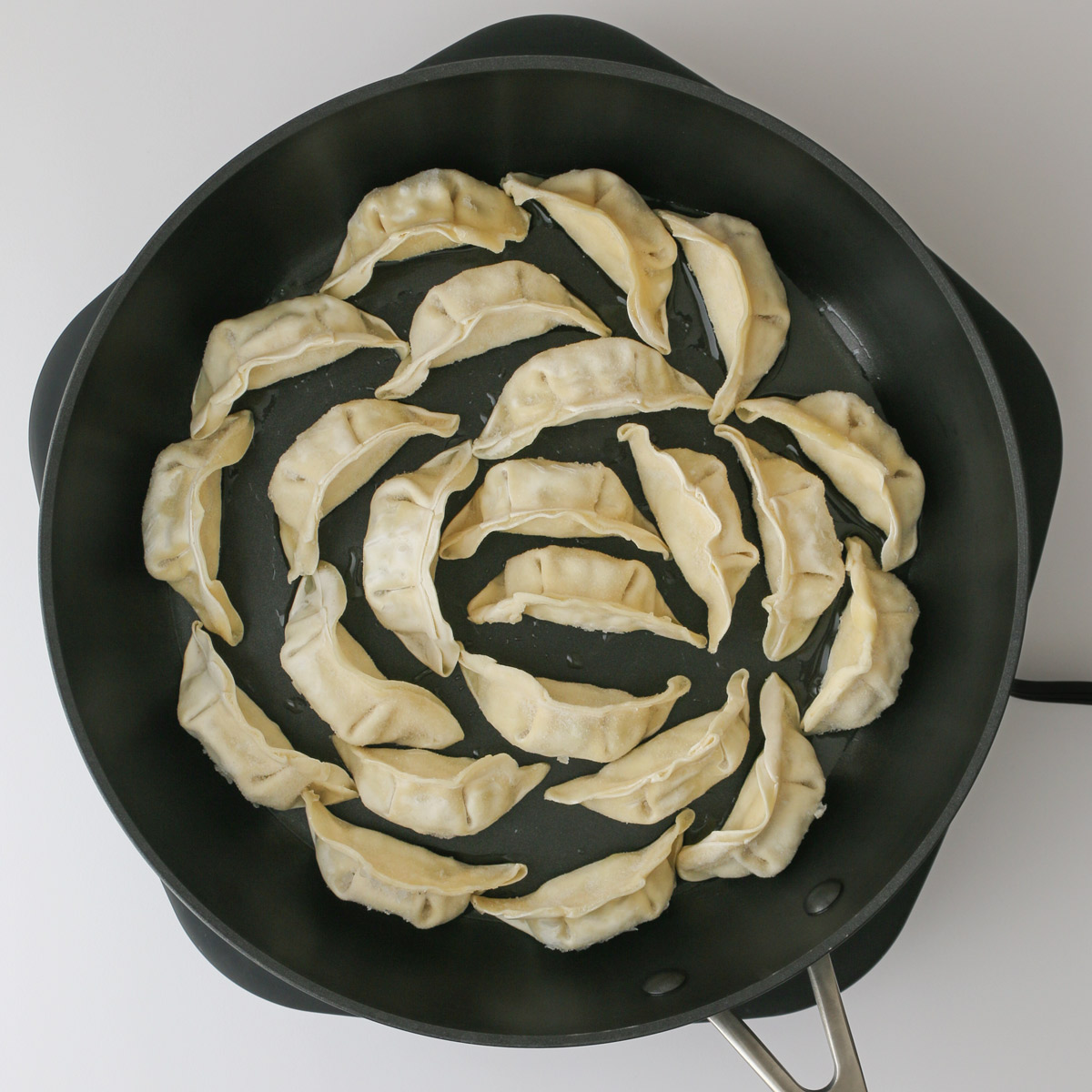 frozen potstickers in large black skillet.