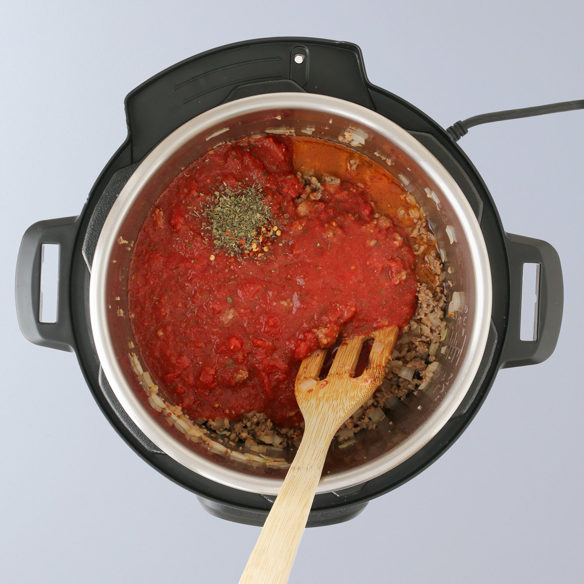 adding sauce and spices to meat in pot.