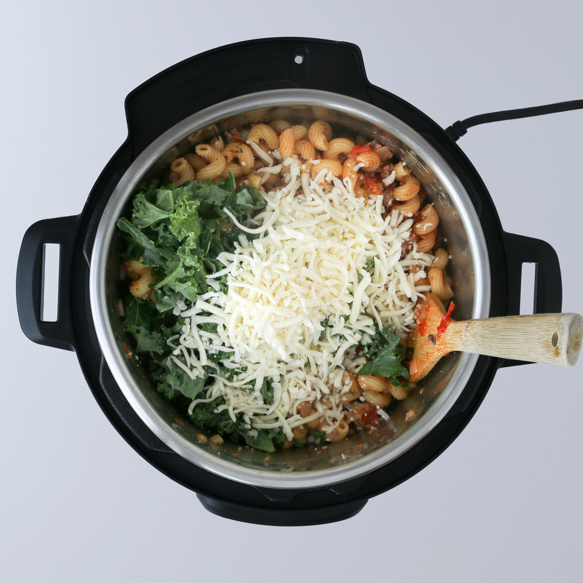 adding kale and cheese to the pasta in the instant  pot.