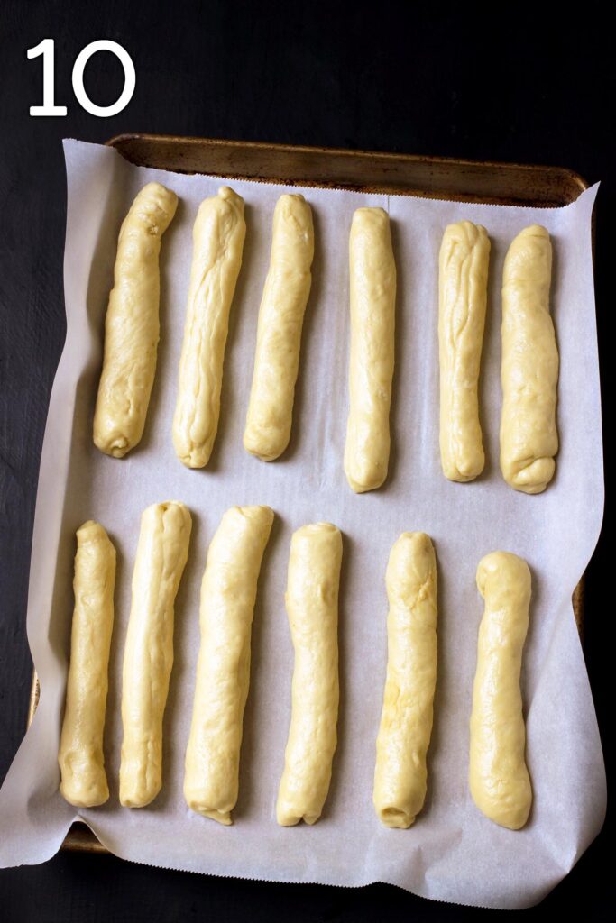 shaped hot dog buns on sheet pan lined with parchment paper.