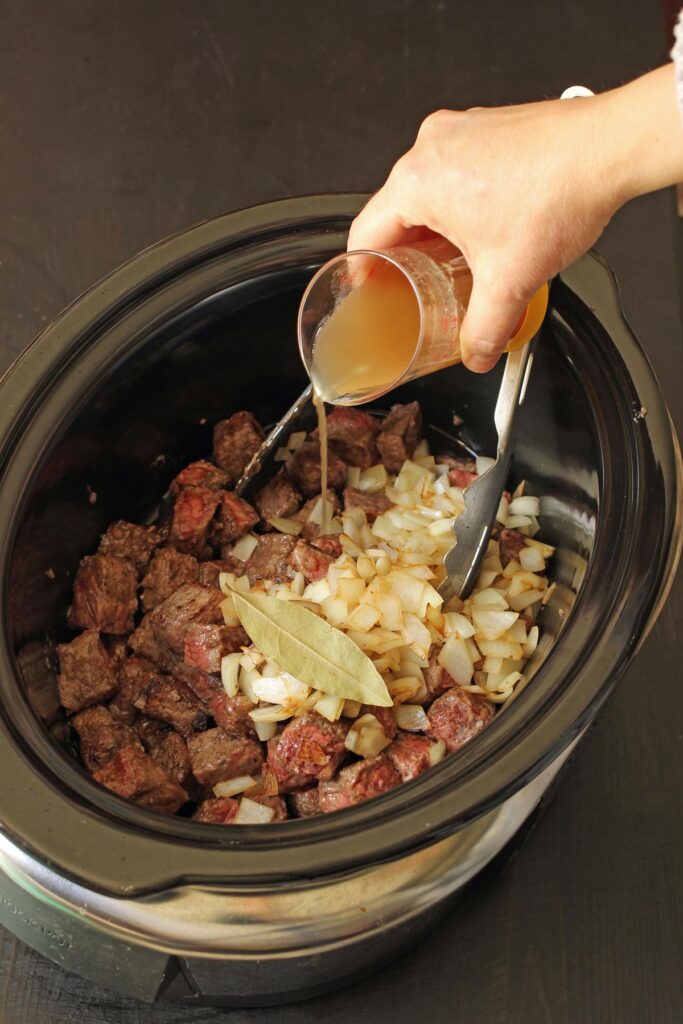 adding broth to meat in crock