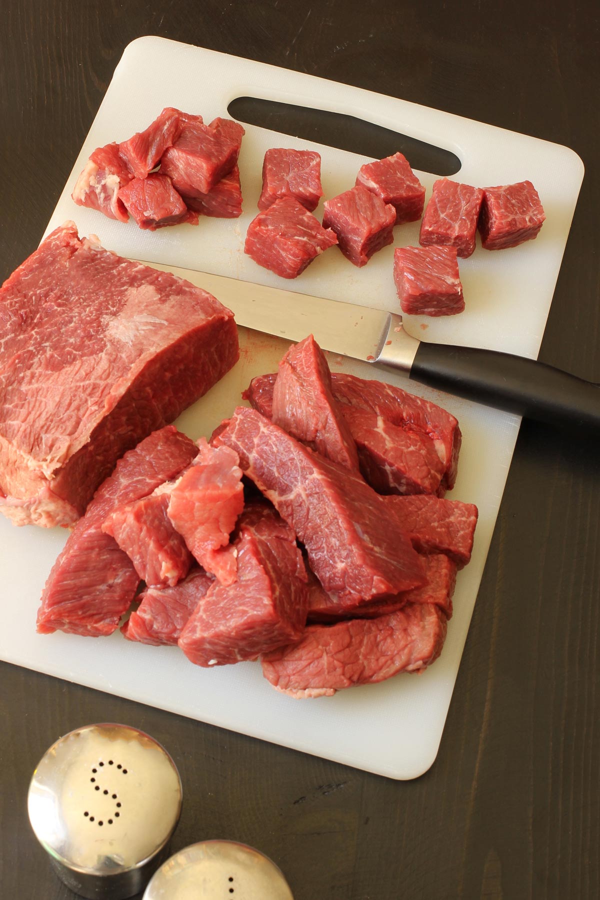 cutting roast into cubes on cutting board