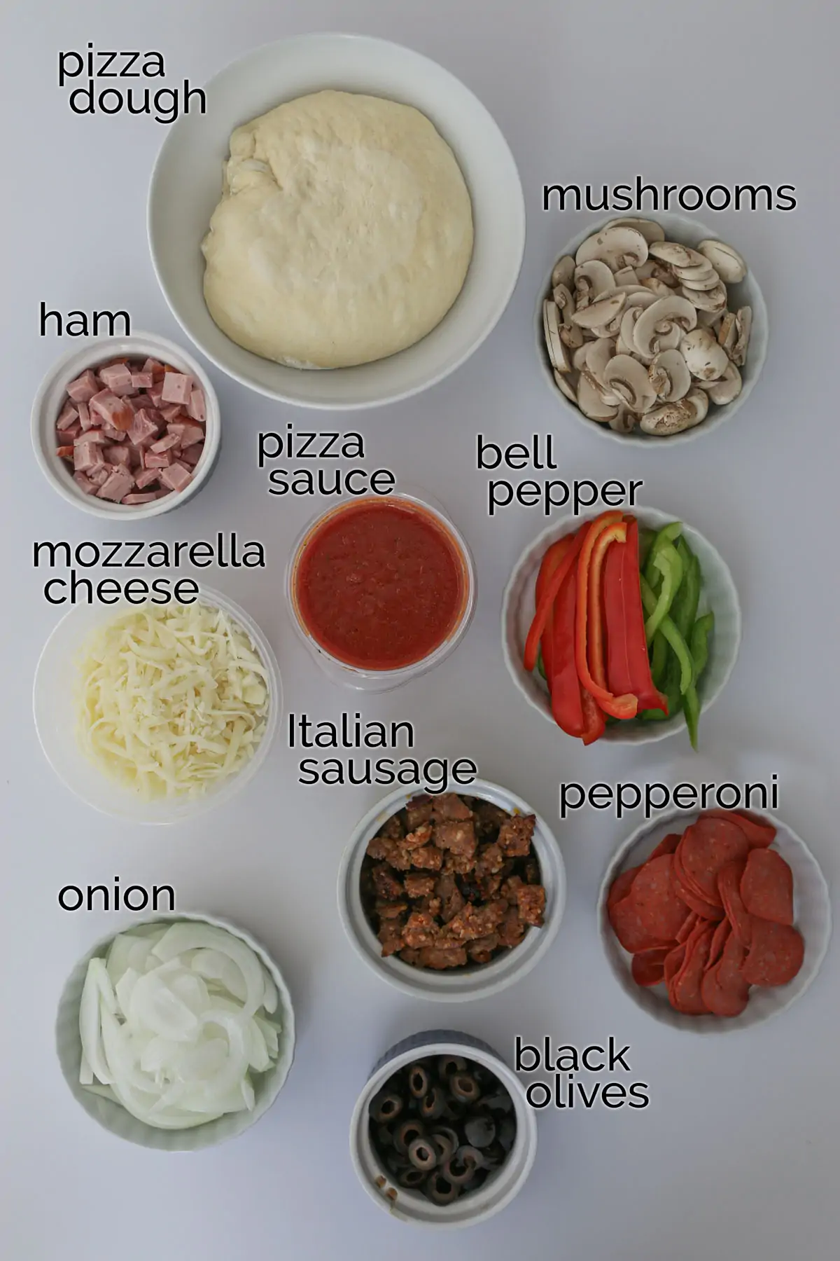 ingredients for supreme pizza laid out on a white table.