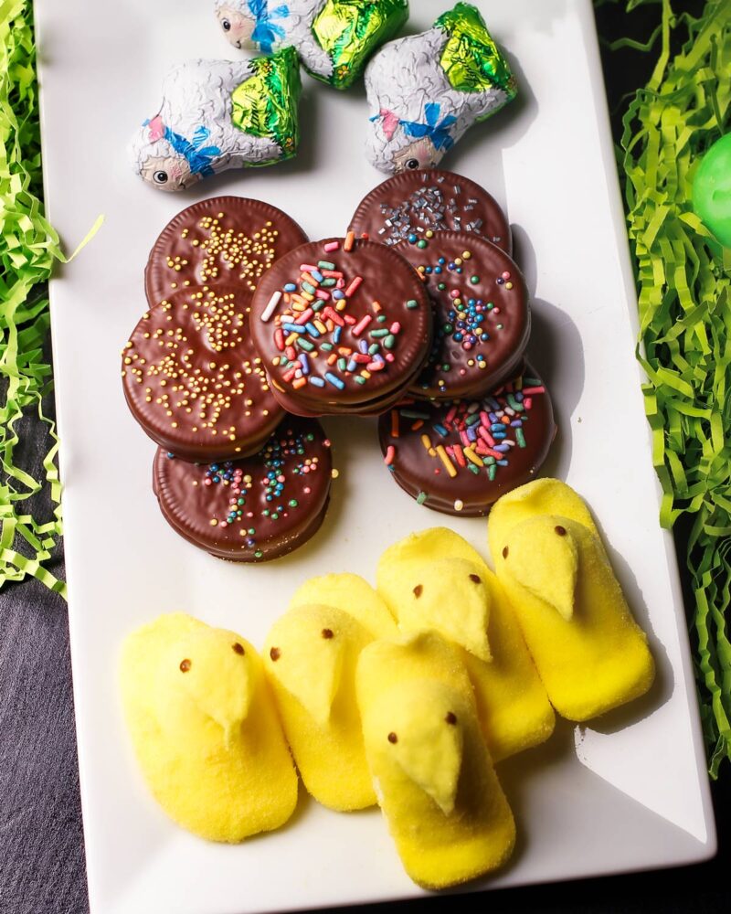 easter themed oreos on plate with paper grass, peeps, and easter candy.