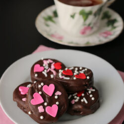 valentine chocolate dipped oreos on a white plate with a pink napkin and a teacup.