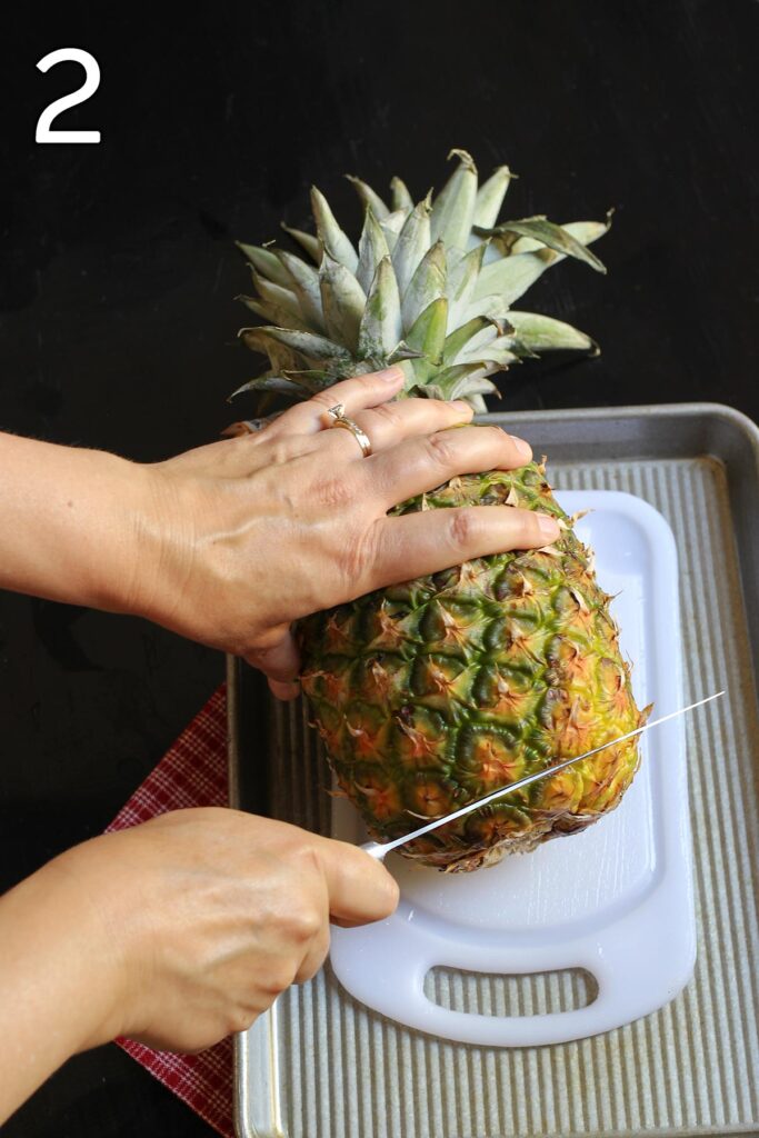 cutting the bottom off the pineapple.