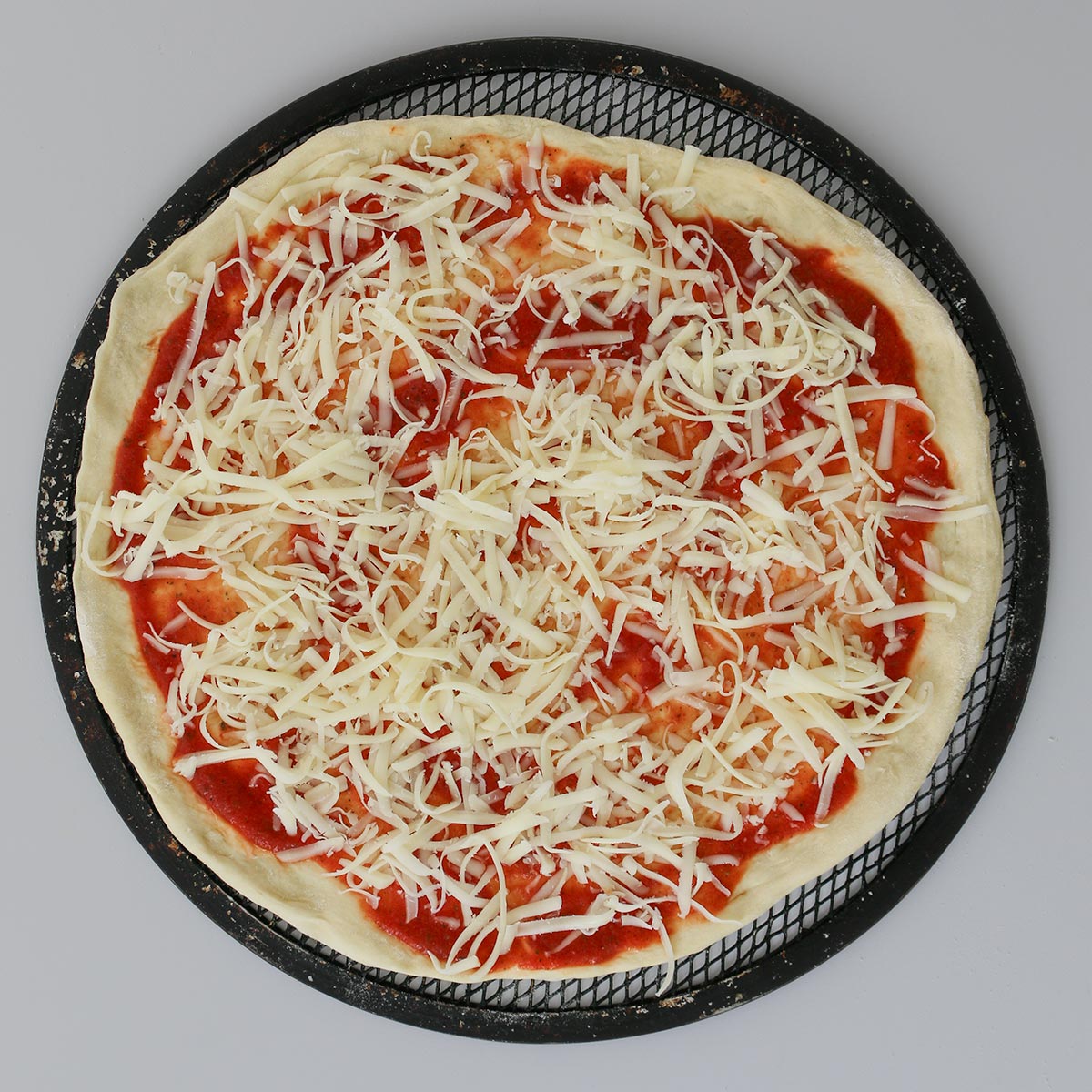 pizza dough round topped with sauce and cheese.