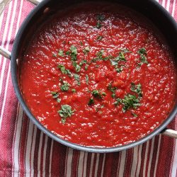 big pot of marinara sauce on red striped cloth