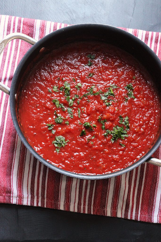 big pot of marinara sauce on red striped cloth