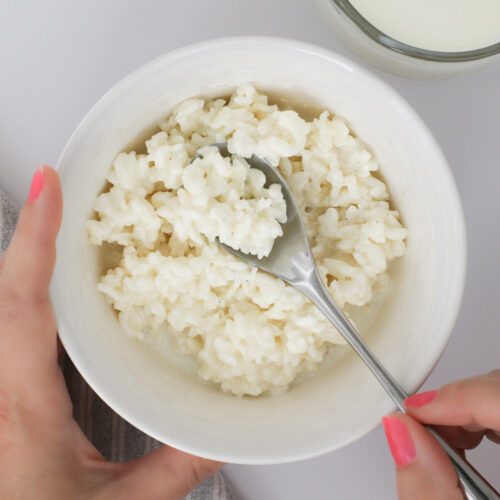spooning up rice pudding from a white bowl.