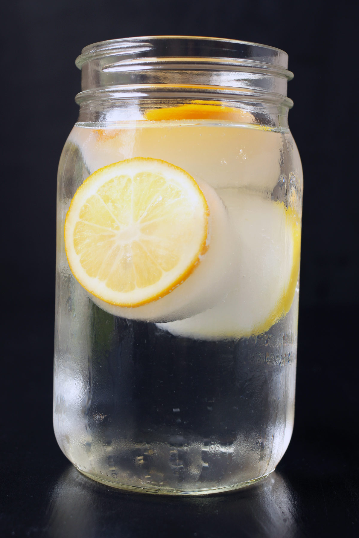 quart sized mason jar with lemon ice cubes and water.