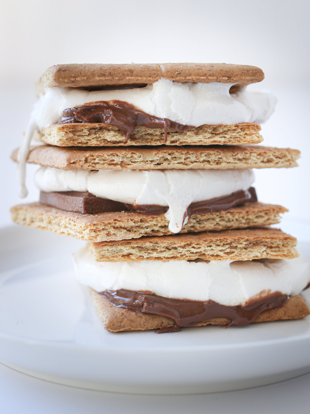 stack of three smores on a white plate with a white background.