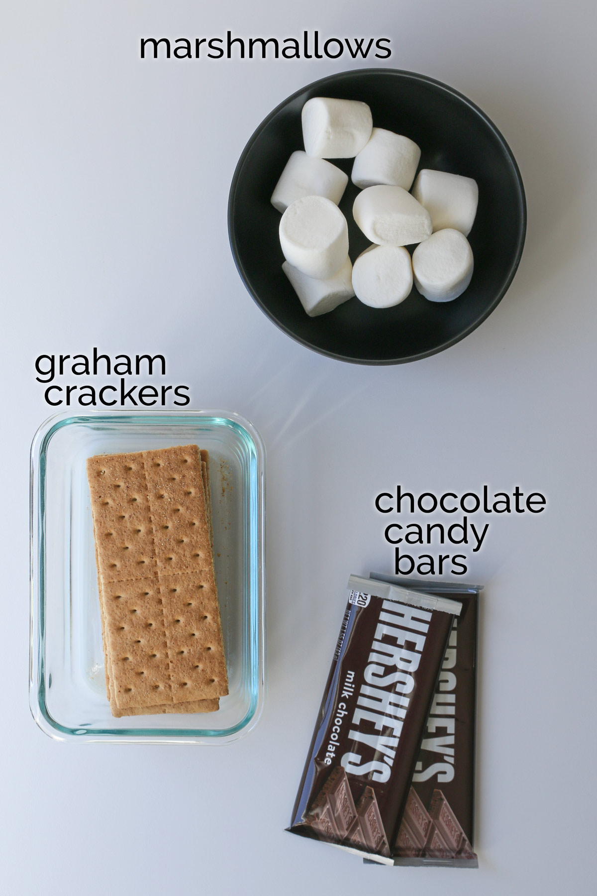 smores ingredients laid out on a white counter.