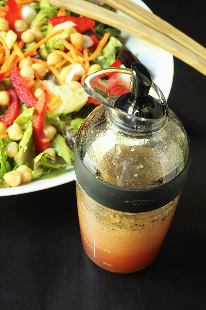 cruet with italian salad dressing next to green salad