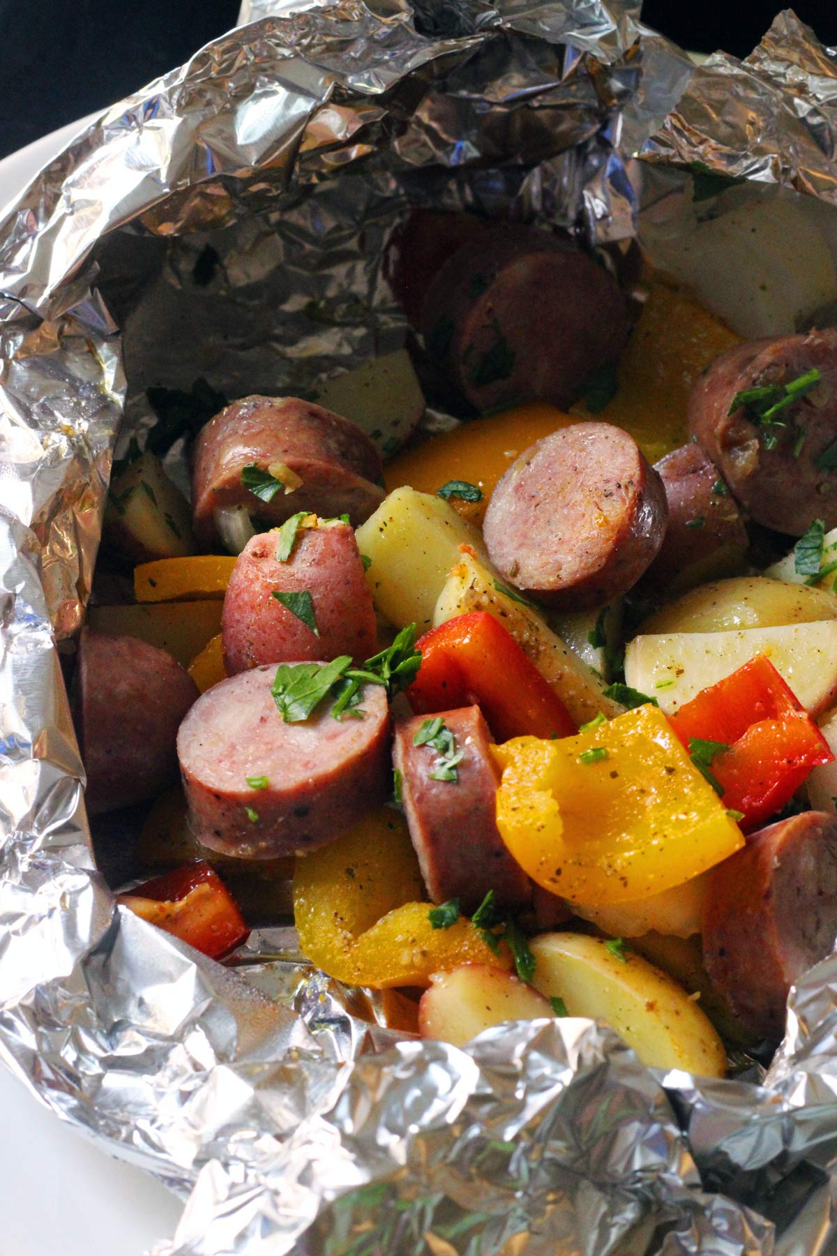 open foil packet of peppers, onions, and sausage.